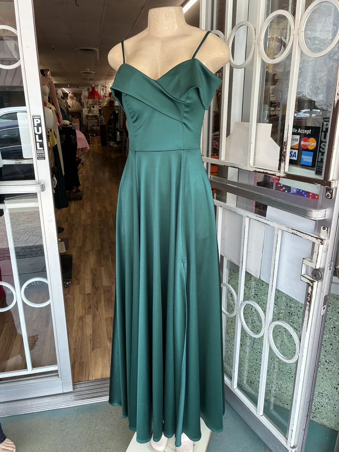 Green off-shoulder evening gown displayed on a mannequin