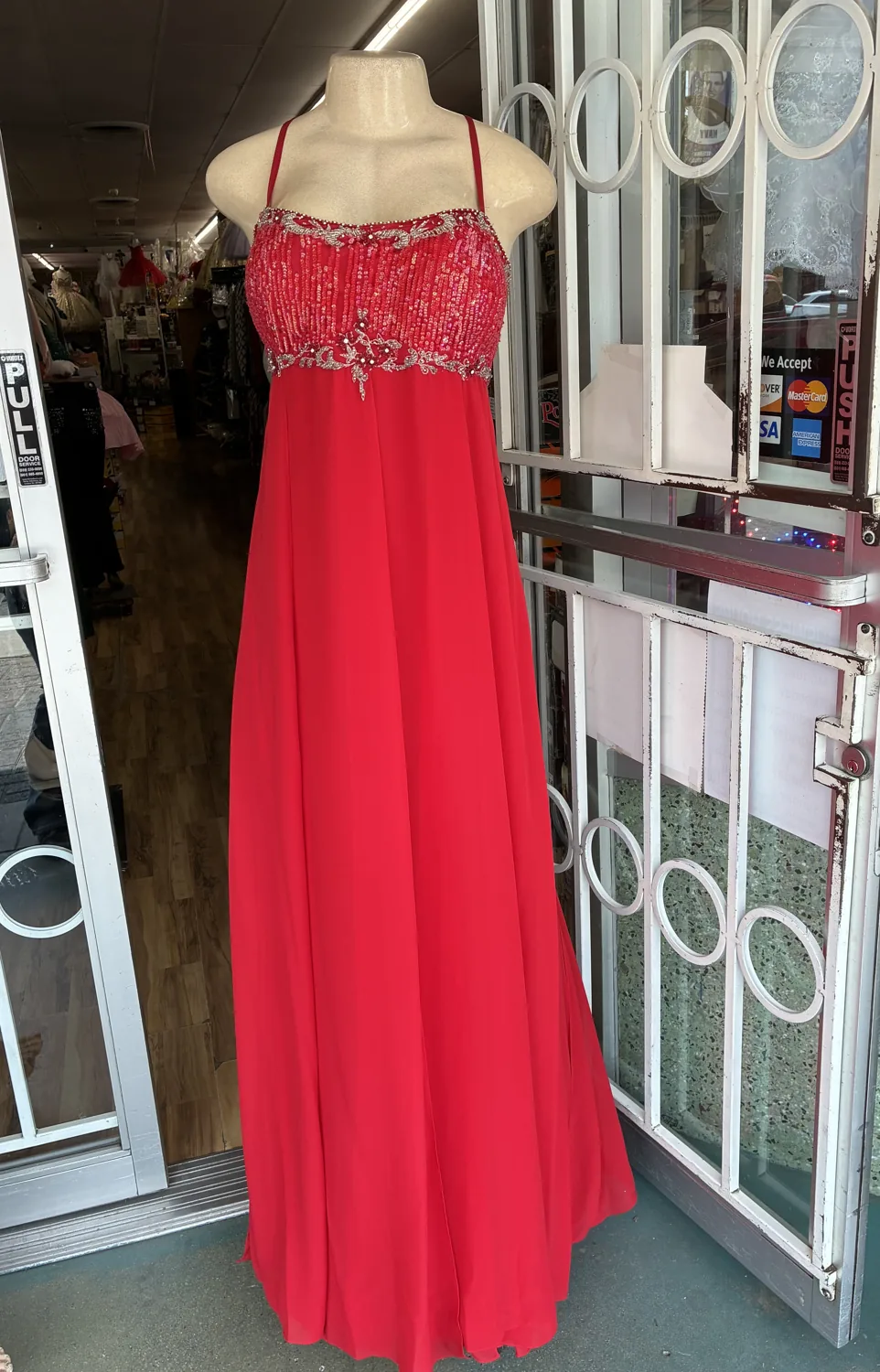 Red embellished evening gown displayed on a mannequin