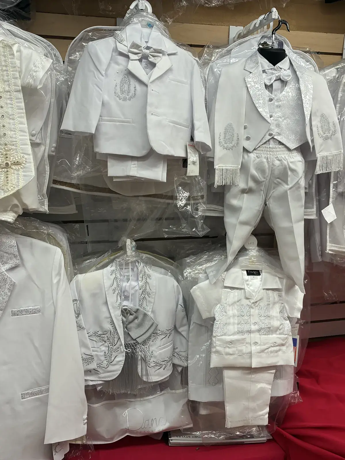 White baptism suits with embroidery on display at Yessenia’s Fashion