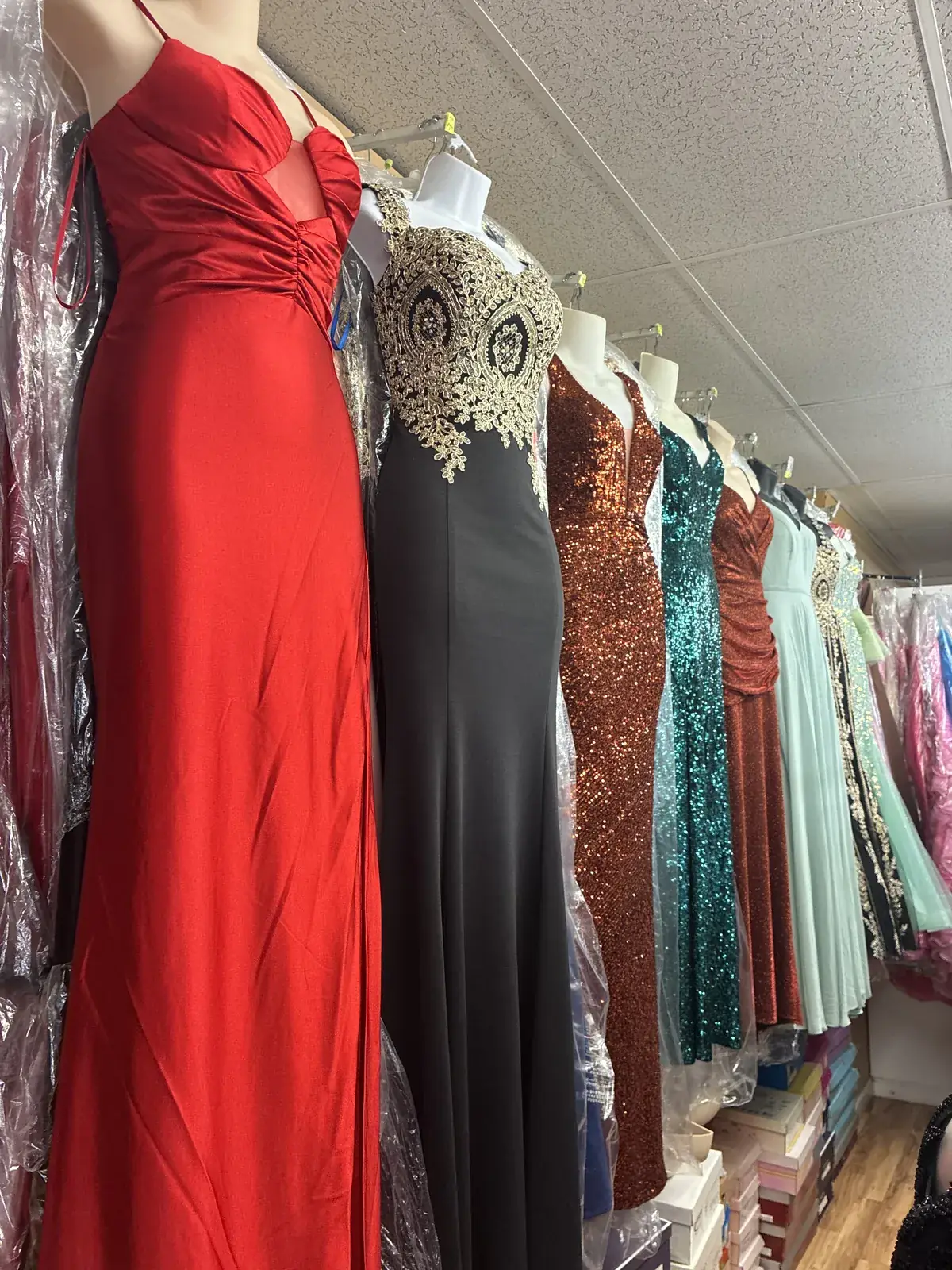 Red gown with our rack of evening dresses on display at Yessenia’s Fashion